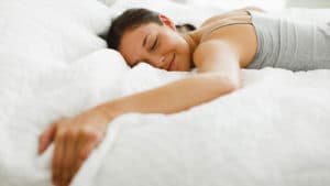 mujer acostada boca abajo en su cama con una sonrisa