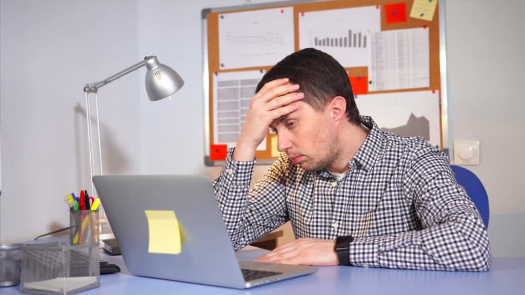 hombre frente a su computadora estresado 